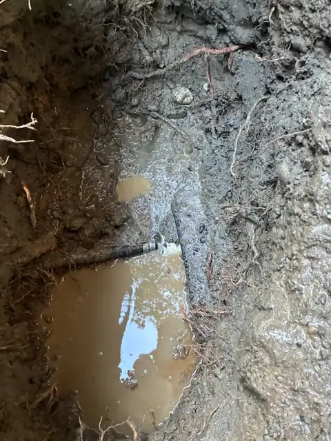 Failed pipe fitting found at the bottom of a muddy excavation pit