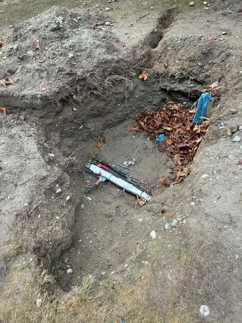 Old PVC and conduit exposed at the bottom of an excavation pit