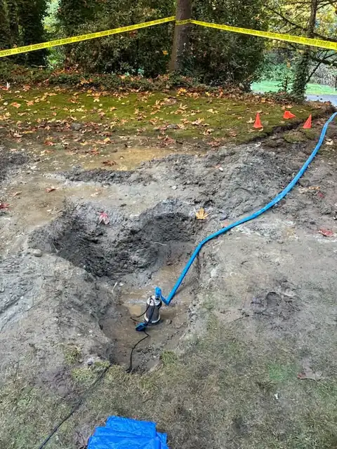 Pump sitting in a flooded pit with caution tape and cones around it