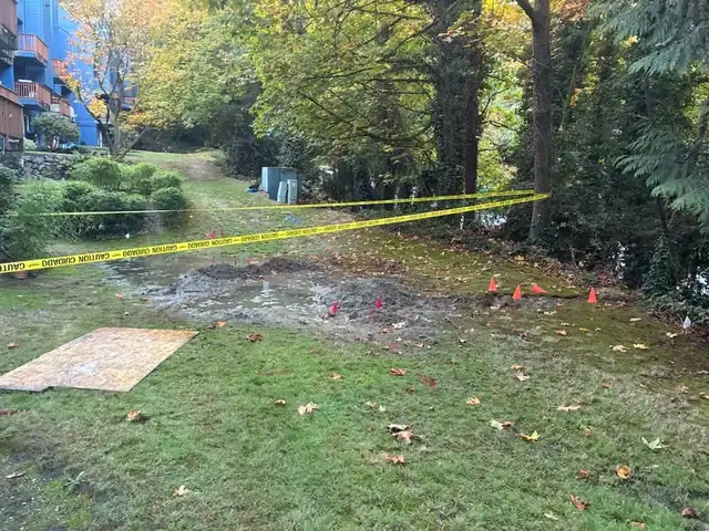 Caution tape across a flooded condominium lawn with marking flags and cones