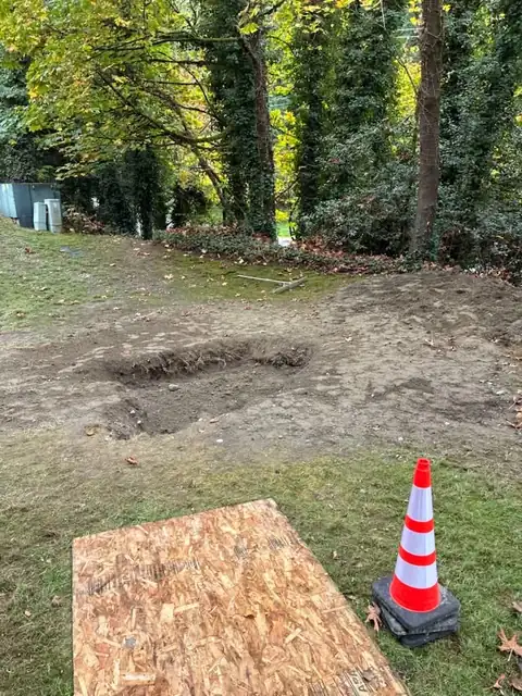 Plywood ground protection and a cone beside a backfilled excavation
