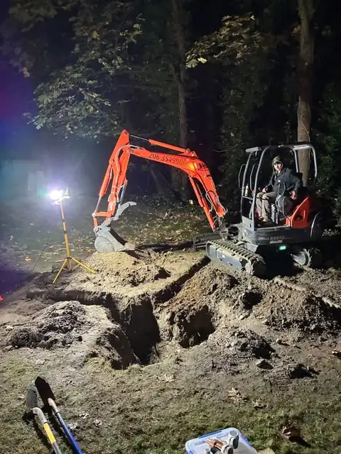Operator in the seat of the 360 Leak Finders mini excavator at a night job site