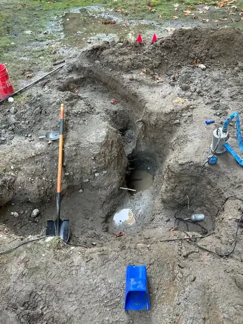Shovel, pump and tools around an excavation pit at a foundation