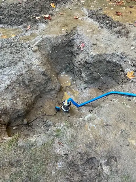 Close view of a submersible pump dewatering a muddy excavation