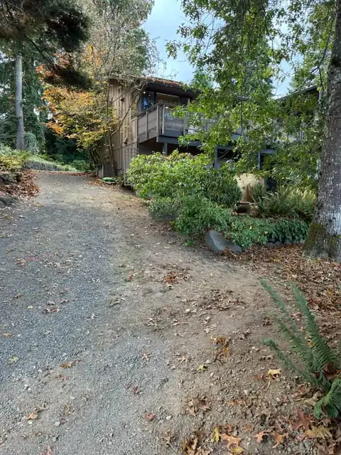 Gravel driveway and landscaping restored below a wooded home