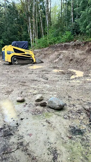 Gehl CTL85 compact track loader on a muddy cleared site with boulders in the foreground