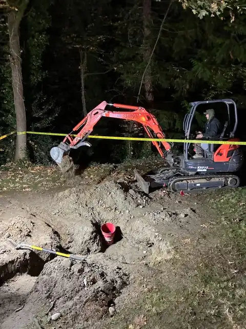 Mini excavator working behind caution tape at night
