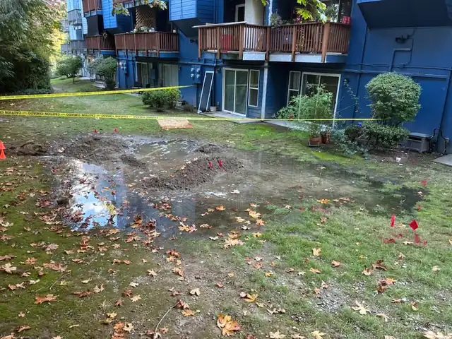 Standing water across a condominium lawn below wooden balconies