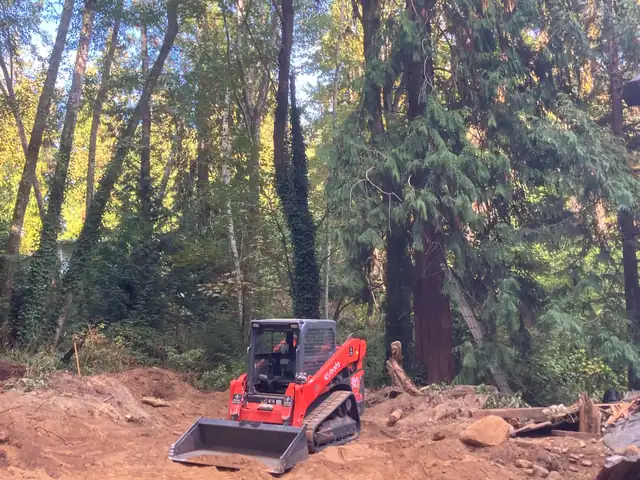 Kubota SVL75-2 compact track loader on a cleared lot under cedars