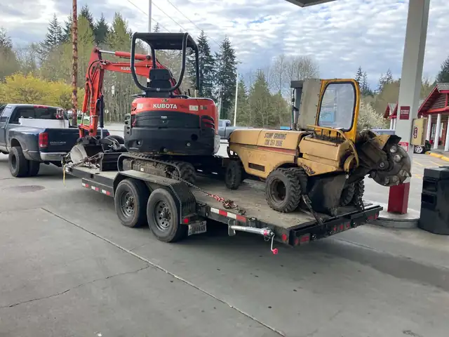 Kubota mini excavator and Rayco stump grinder chained down on an equipment trailer