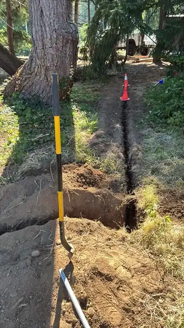 Hand-dug trench along a tree root zone with a shovel and safety cone