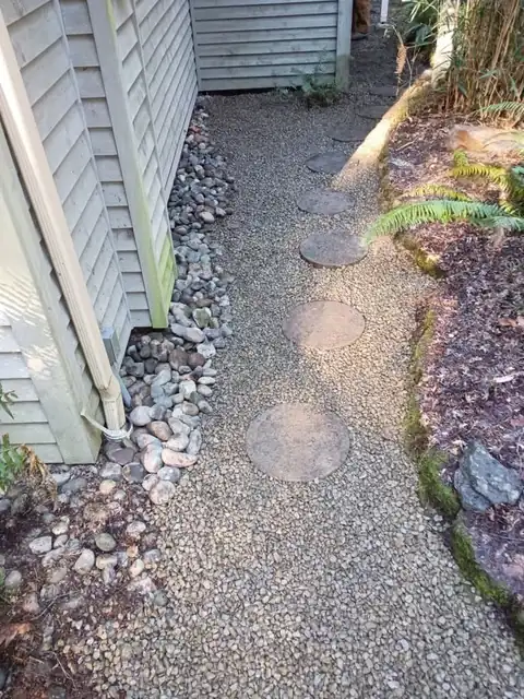 Gravel side-yard path with round stepping stones fully restored after a water line replacement