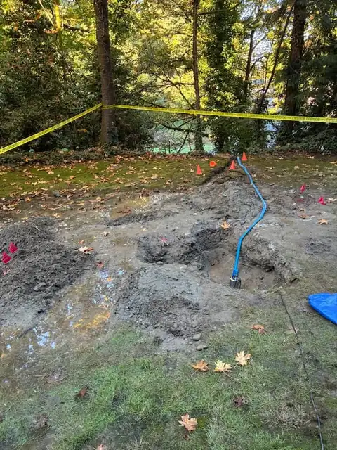 Caution tape around a flooded lawn with a pump running in the excavation